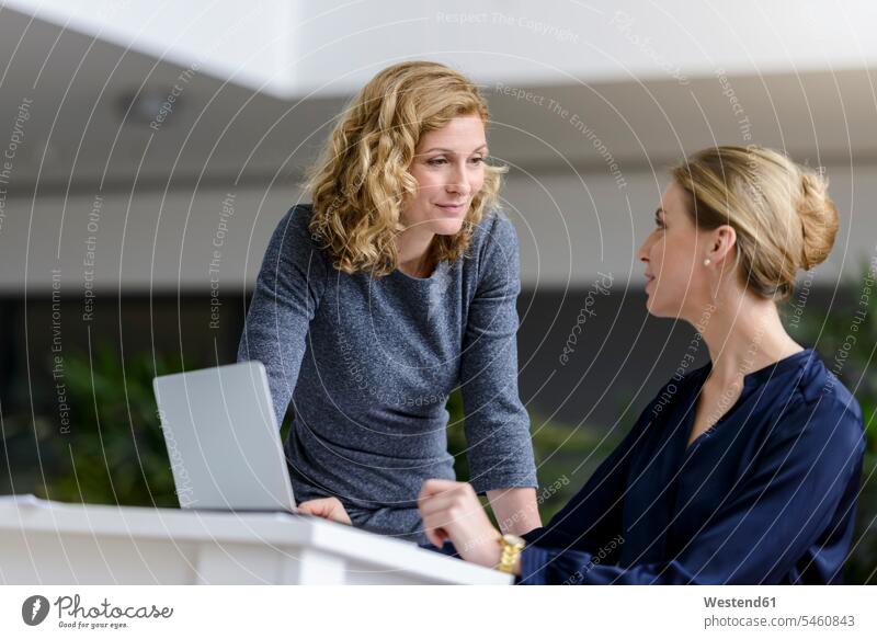 Zwei Frauen sprechen am Schreibtisch im Büro Arbeitskollege Arbeitskollegen Kollege Partner Partnerschaften Job Berufe Berufstätigkeit Beschäftigung Jobs