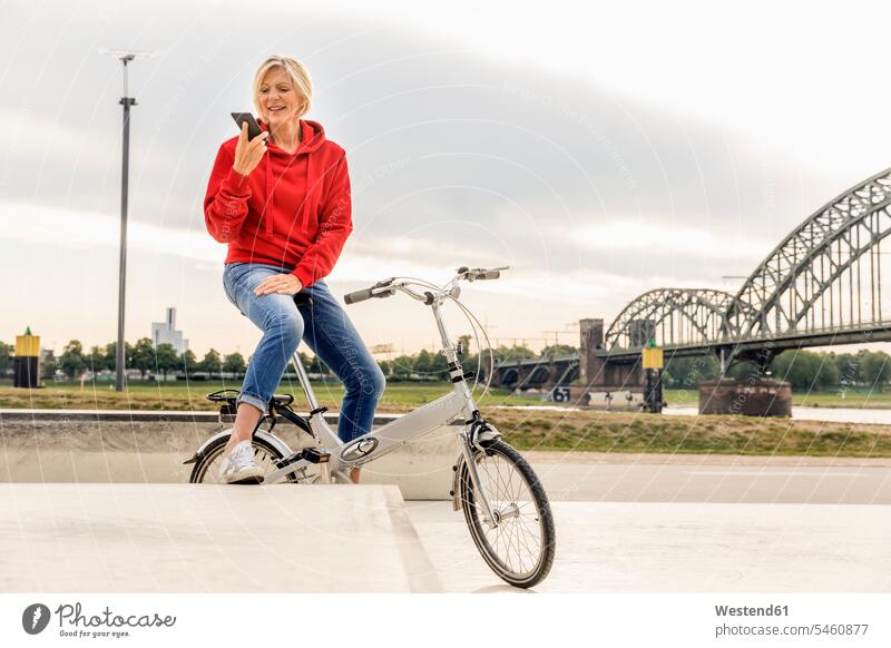Ältere Frau mit Stadtrad mit Mobiltelefon Fahrrad Bikes Fahrräder Räder Rad Zuversicht Zuversichtlich Selbstvertrauen selbstbewusst Vertrauen Handy Handies