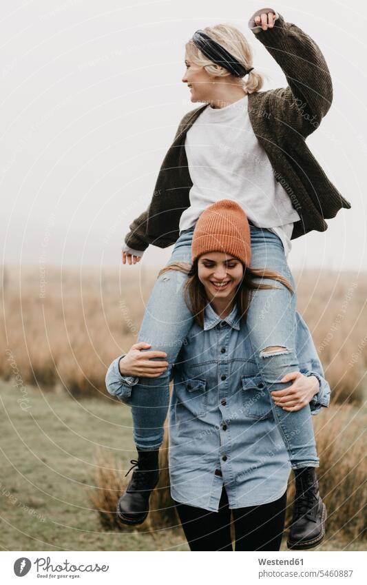 Großbritannien, Schottland, Isle of Skye, glückliche Frau trägt Freund Huckepack in ländlicher Landschaft Freundinnen weiblich Frauen tragen transportieren