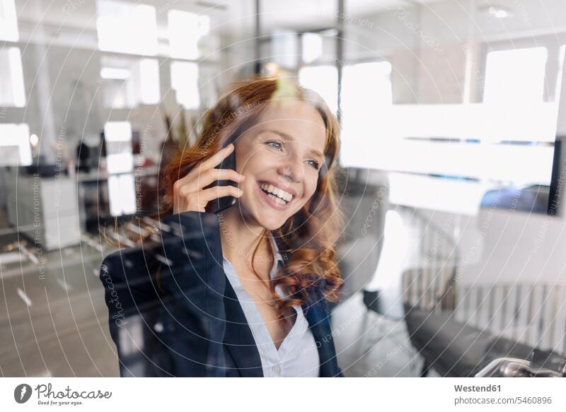 Glückliche rothaarige Geschäftsfrau am Telefon im Büro Leute Menschen People Person Personen Europäisch Kaukasier kaukasisch 1 Ein ein Mensch eine