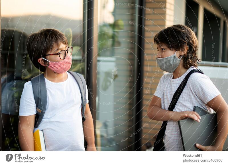 Geschwister tragen Masken im Freien Ausbildung Schueler Schulkinder Schüler Rucksäcke Bücher T-Shirts Brillen stehend steht geschützt schützen Absicherung
