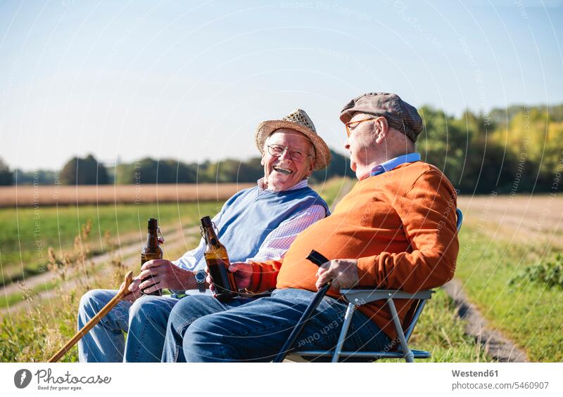 Zwei alte Freunde sitzen auf den Feldern, trinken Bier und reden über alte Zeiten sprechen sitzend sitzt Beste Freunde Bester Freund Alkohol