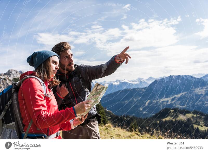 Österreich, Tirol, junges Paar mit Karte in Berglandschaft beim Herumschauen Gebirge Gebirgslandschaft Gebirgskette Gebirgszug Berge Landkarte Landkarten
