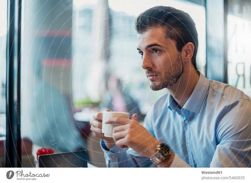 Junger Geschäftsmann trinkt Kaffee in einem Café Businessmann Businessmänner Geschäftsmänner Cafe Kaffeehaus Bistro Cafes Cafés Kaffeehäuser trinken