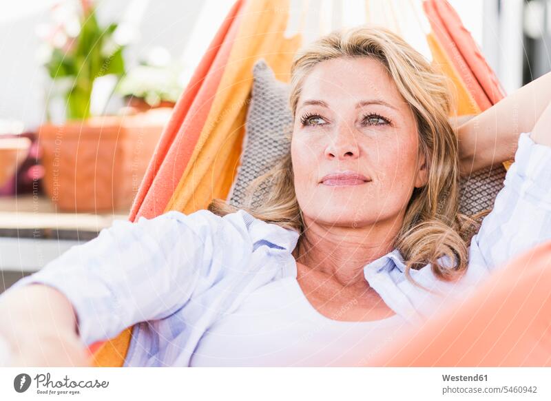 Porträt einer nachdenklichen, reifen Frau, die sich in der Hängematte entspannt Polster Hängematten entspannen relaxen liegend liegt daheim zu Hause Muße