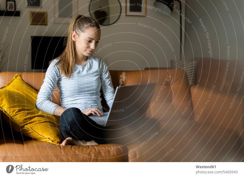Junge Frau benutzt Laptop zu Hause auf der Couch Leute Menschen People Person Personen Alleinstehende Alleinstehender Singles Unverheiratete Unverheirateter Job