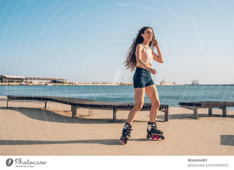 Junge Frau beim Inlineskaten auf der Promenade an der Küste freuen Glück glücklich sein glücklichsein zufrieden Muße trainieren auf Achse in Bewegung außen