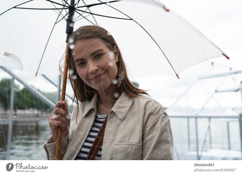 Nahaufnahme einer lächelnden jungen Frau mit Regenschirm, die während des Regens in der Stadt steht Farbaufnahme Farbe Farbfoto Farbphoto Niederlande Holland