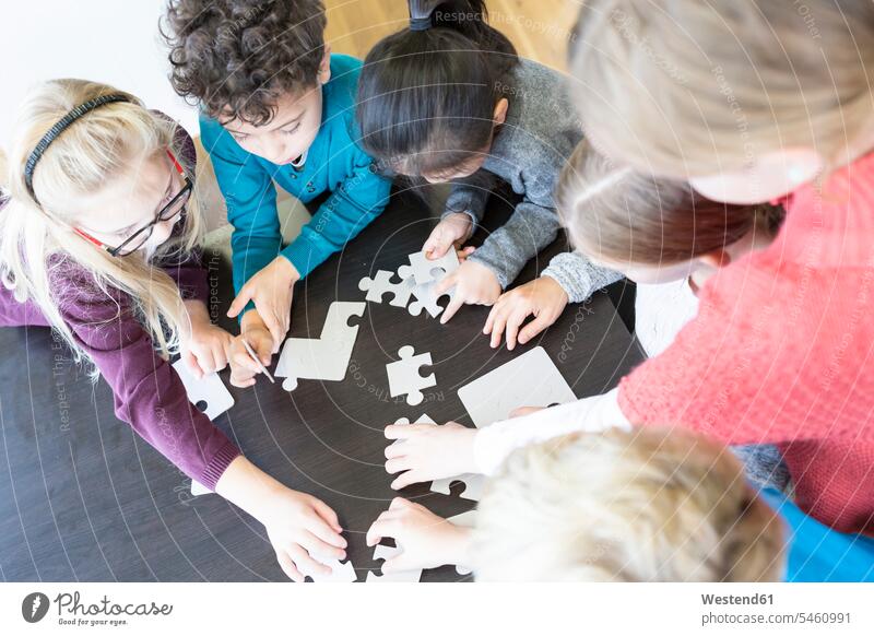 Schülerinnen und Schüler spielen gemeinsam Puzzle in der Schule Schulen Puzzlespiel Gemeinsam Zusammen Miteinander Schulkind Schueler Schulkinder Bildung