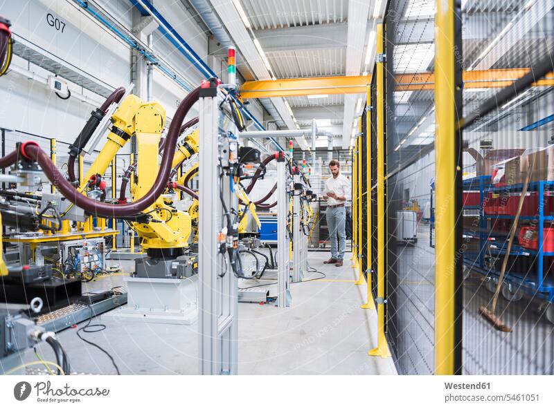 Selbstbewusster Ingenieur in voller Länge in automatisierter Roboterfabrik Farbaufnahme Farbe Farbfoto Farbphoto Deutschland Innenaufnahme Innenaufnahmen innen