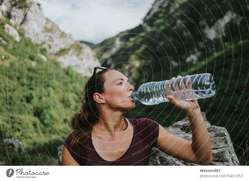 Mittlere erwachsene weibliche Wanderin, die aus einer Plastikflasche trinkt und dabei wegschaut Farbaufnahme Farbe Farbfoto Farbphoto Ruta de las Xanas Spanien