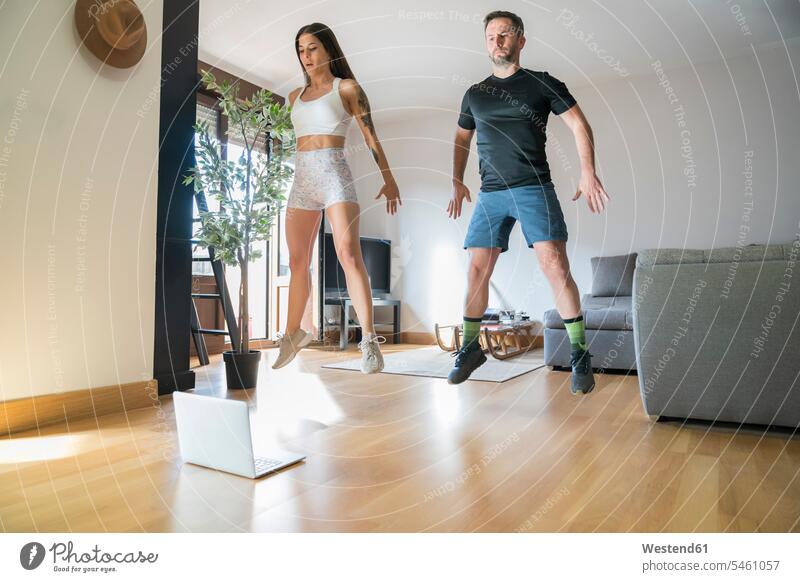 Paar springt beim Training zu Hause auf Parkettboden Farbaufnahme Farbe Farbfoto Farbphoto Spanien Innenaufnahme Innenaufnahmen innen drinnen Innenausstattung