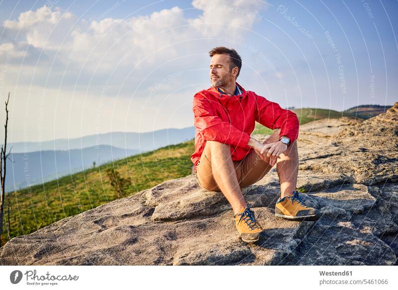 Mann sitzt auf Fels und genießt ruhige Momente beim Wandern wandern Wanderung genießen geniessen Genuss Berg Berge Männer männlich sitzen sitzend Felsen