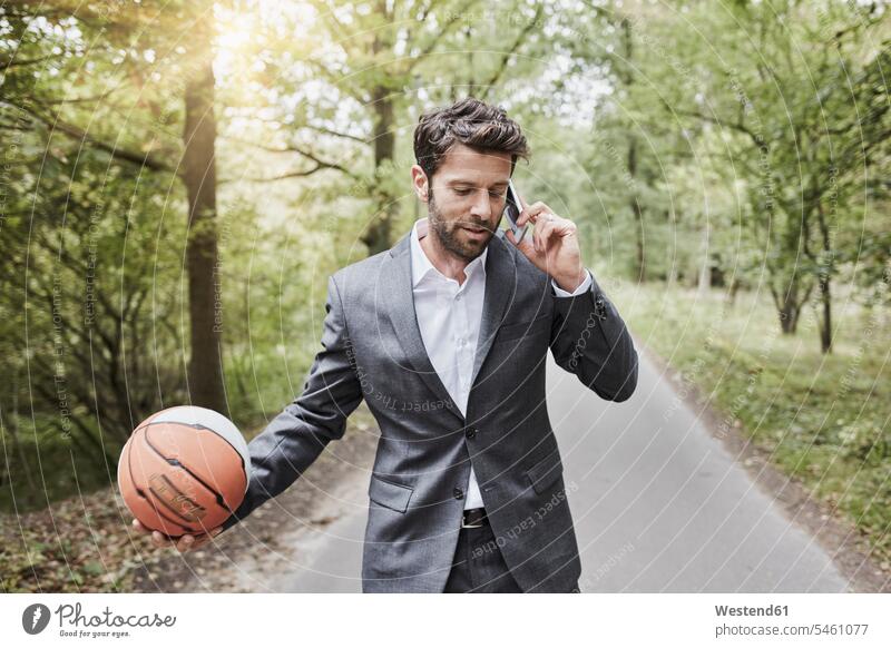 Geschäftsmann mit Basketballgespräch auf dem Smartphone auf der Landstraße telefonieren anrufen Anruf telephonieren Businessmann Businessmänner Geschäftsmänner