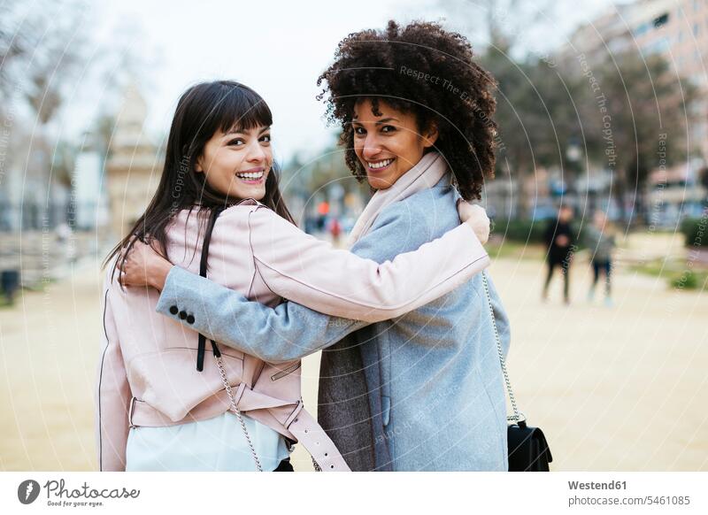 Spanien, Barcelona, Porträt zweier glücklicher Frauen im Stadtpark, die sich umarmend umdrehen Freundinnen weiblich staedtisch städtisch Portrait Porträts