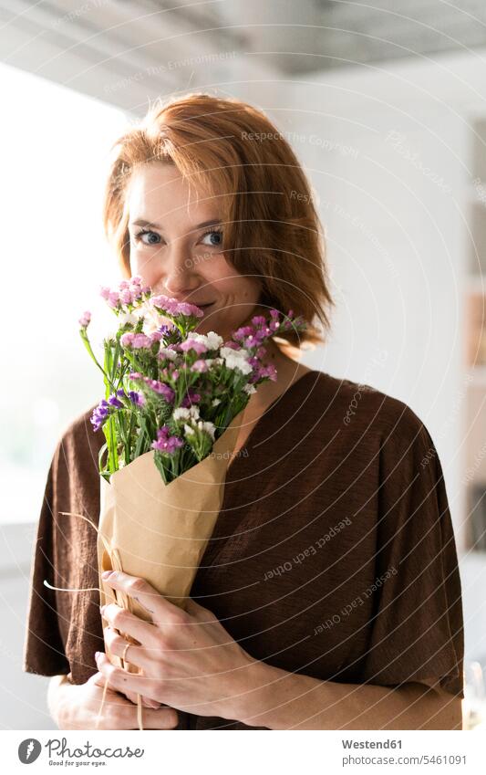 Rothaarige Frau riecht Blumenstrauß Europäer Kaukasier Europäisch kaukasisch Oberkörper Oberkörperaufnahmen Halbfigur halten glücklich Glück glücklich sein