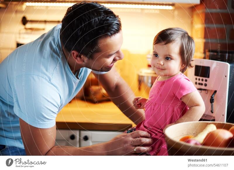 Lächelnde Vater Blick auf Baby-Mädchen sitzt auf Zähler in der Küche zu Hause Arbeitsplatte Arbeitsplatten Babies Babys Säuglinge Kind Kinder Zuhause daheim