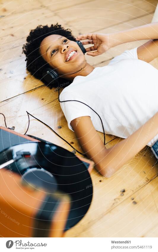 Junge Frau hört zu Hause Vinyl-Schallplatten, liegt am Boden Musik hören Plattenspieler Kopfhörer Kopfhoerer junge Frau junge Frauen analog Medien Medium