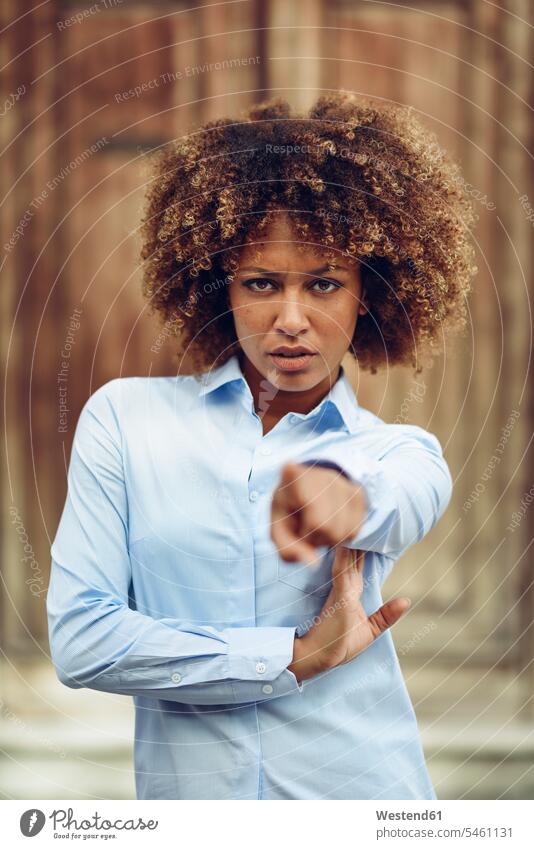 Porträt einer ernsten Frau mit Afro-Frisur, die mit dem Finger nach draussen zeigt Portrait Porträts Portraits deuten weiblich Frauen Afro-Look Afros Afrolook