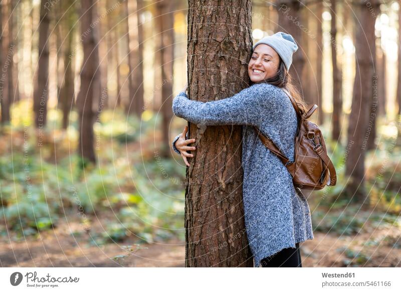 Glückliche Wanderin umarmt Baum beim Wandern im Wald von Cannock Chase im Winter Farbaufnahme Farbe Farbfoto Farbphoto Außenaufnahme außen draußen im Freien Tag
