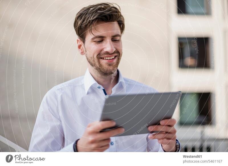 Lächelnder Geschäftsmann in der Stadt mit Tablet Businessmann Businessmänner Geschäftsmänner Tablet Computer Tablet-PC Tablet PC iPad Tablet-Computer lächeln