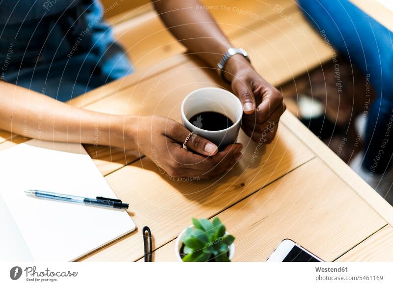 Hochwinkelaufnahme einer Frau, die im Café schwarzen Kaffee am Tisch hält Farbaufnahme Farbe Farbfoto Farbphoto Innenaufnahme Innenaufnahmen innen drinnen Tag