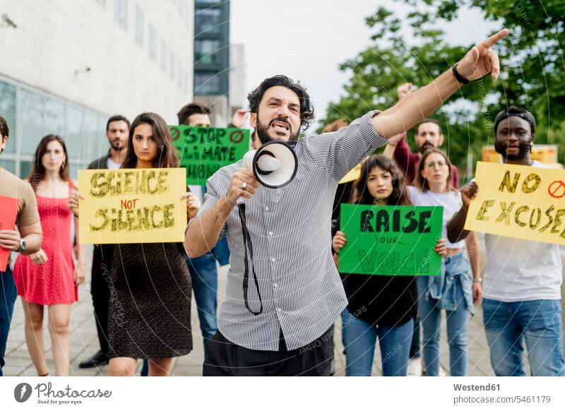Mann schreit durch ein Megafon, während er mit Menschen auf der Straße protestiert Farbaufnahme Farbe Farbfoto Farbphoto Freizeitkleidung Freizeitbekleidung