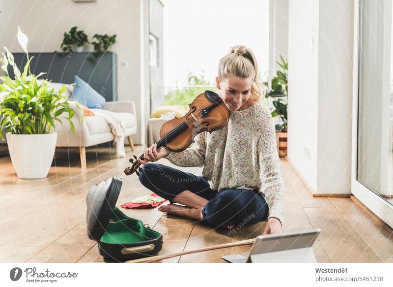 Frau mit Tablet sitzt auf dem Boden zu Hause spielen Geige Leute Menschen People Person Personen Alleinstehende Alleinstehender Singles Unverheiratete