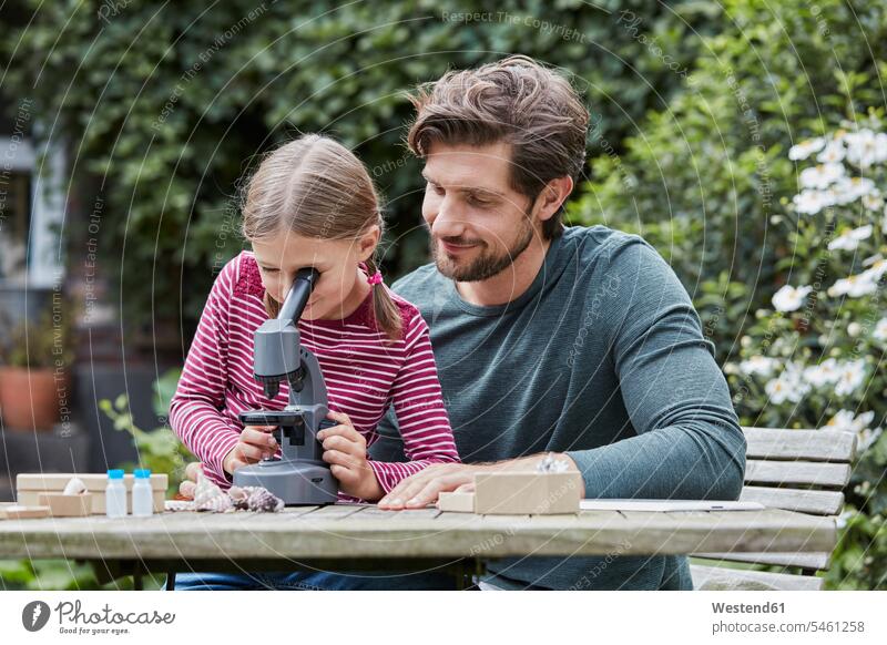 Vater und Tochter verwenden Mikroskop zusammen am Gartentisch Gemeinsam Zusammen Miteinander Töchter Terrassentisch Mikroskope Papas Väter Vati Vatis Papis Kind