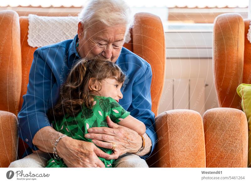 Großmutter umarmt ihre Enkelin im Wohnzimmer Leute Menschen People Person Personen Europäisch Kaukasier kaukasisch 2 2 Menschen 2 Personen zwei Zwei Menschen