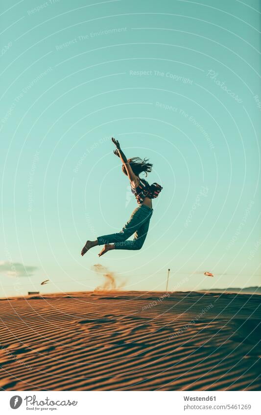 Junge Frau springt in Wüstenlandschaft springen hüpfen Landschaft Landschaften weiblich Frauen Sprung Spruenge Sprünge Erwachsener erwachsen Mensch Menschen