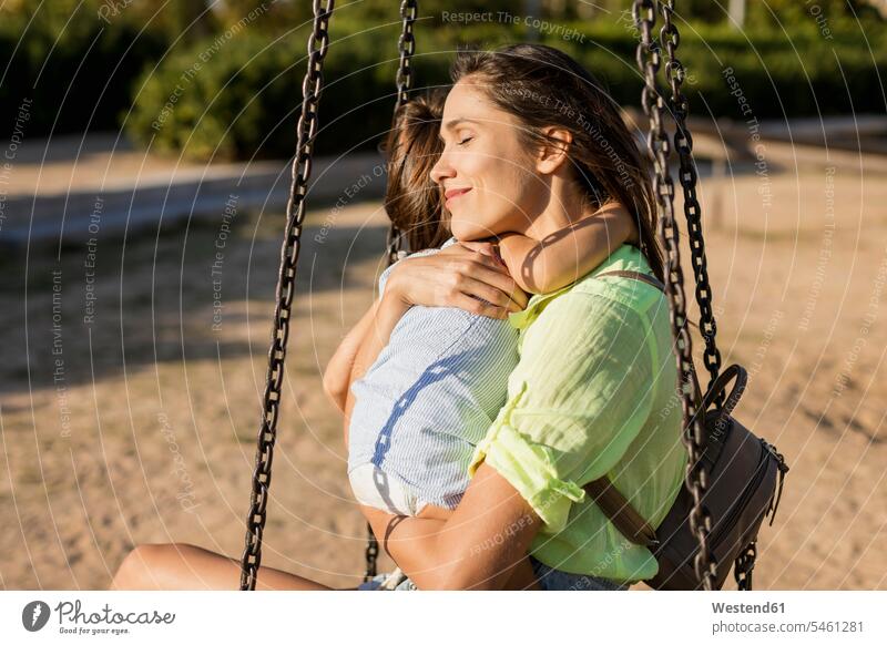 Lächelnde Mutter umarmt Tochter auf einem Spielplatz umarmen Umarmung Umarmungen Arm umlegen Spielplätze Spielfeld Spielplaetze Töchter lächeln Mami Mutti