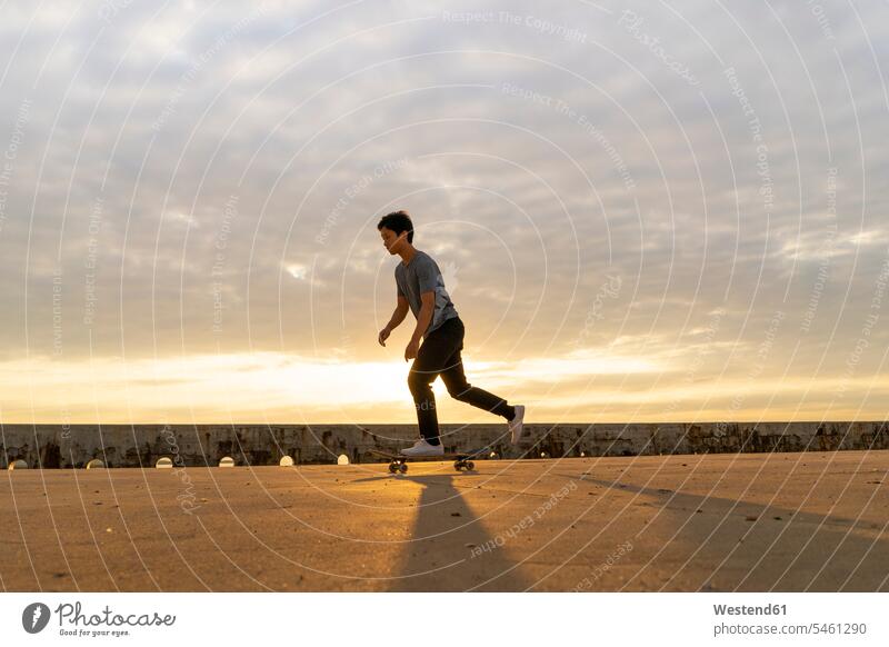 Junger Chinese fährt Skateboard bei Sonnenaufgang in Strandnähe Chinesen chinesisches chinesischer Chinesisch jung Rollbretter Skateboards Beach Straende
