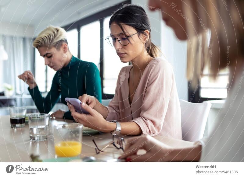 Geschäftsfrau benutzt Smartphone während der Mittagspause im Büro Job Berufe Berufstätigkeit Beschäftigung Jobs geschäftlich Geschäftsleben Geschäftswelt