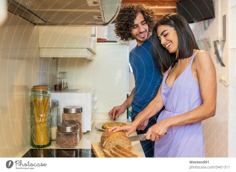 Lächelndes junges Paar bereitet zu Hause in der Küche eine Mahlzeit zu Farbaufnahme Farbe Farbfoto Farbphoto Spanien Freundschaft Kameradschaft Freunde