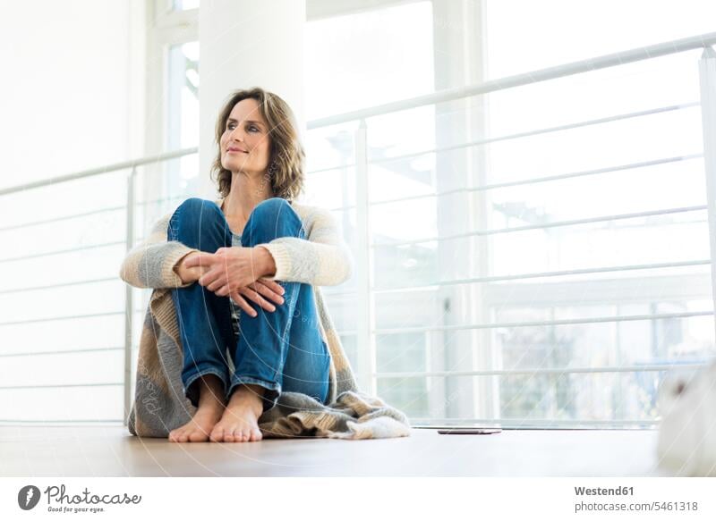 Entspannte Frau sitzt zu Hause auf dem Boden entspannt entspanntheit relaxt Böden Boeden sitzen sitzend lächeln Zuhause daheim weiblich Frauen Entspannung