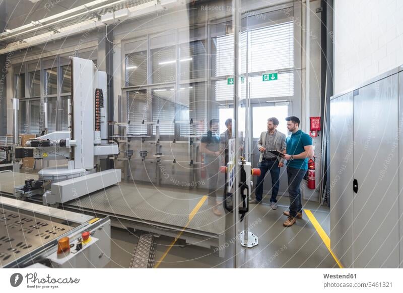 Zwei Männer betrachten eine Maschine in einer modernen Fabrik Mann männlich Maschinen ansehen Fabriken Erwachsener erwachsen Mensch Menschen Leute People