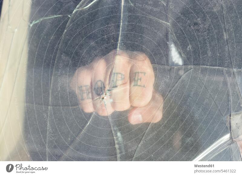 Faust eines jungen Mannes mit HOPE-Tattoo hinter kaputter Windschutzscheibe auf einem Schrottplatz Glasscheiben Transport Transportwesen KFZ Verkehrsmittel