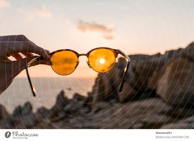 Männerhand hält Sonnenbrille vor der Abendsonne, Nahaufnahme halten Sonnenbrillen Brille Hand Hände Mann männlich Mensch Menschen Leute People Personen