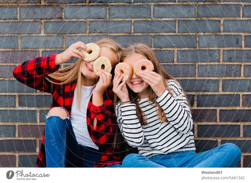 Zwei Mädchen haben Spaß mit Krapfen Donut Doughnut Donuts Doughnuts Spass Späße spassig Spässe spaßig weiblich Gebäck Backware Gebaeck Backwaren Süßspeise