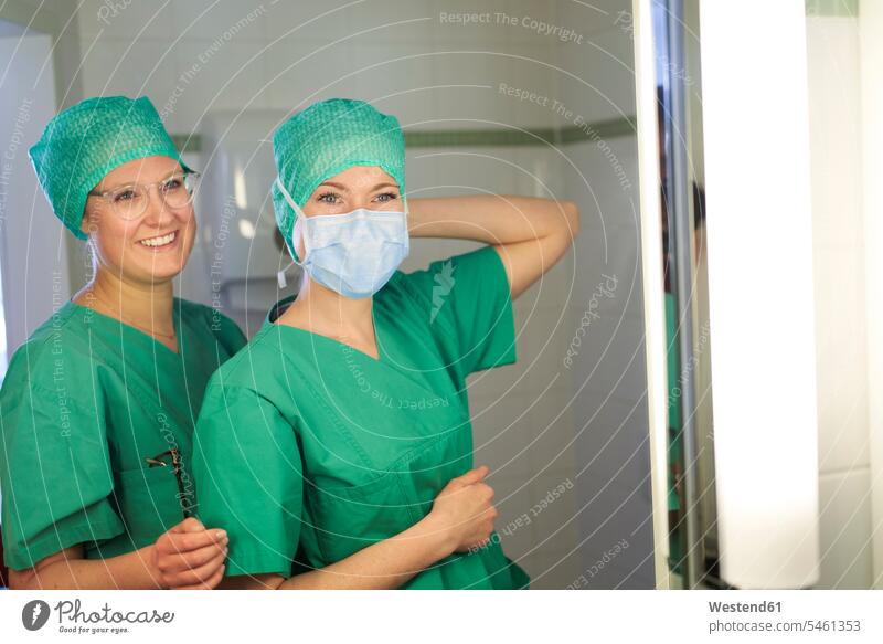 Zwei lächelnde Frauen in Kitteln bereiten sich auf eine Operation vor Gesundheit gesund Einsatz Engagement Hingabe Eifer OP Operationen operieren Chirurgie