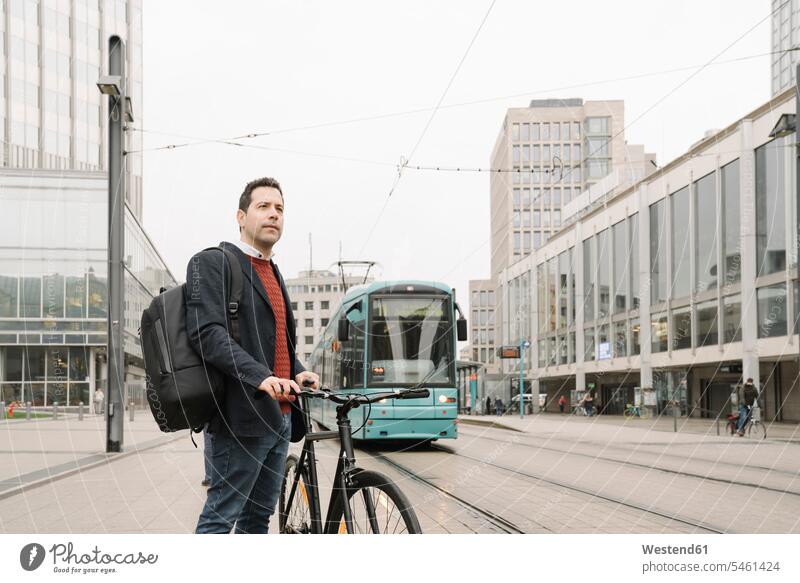 Unternehmer mit Fahrrad steht gegen Seilbahn in der Stadt, Frankfurt, Deutschland Farbaufnahme Farbe Farbfoto Farbphoto Außenaufnahme außen draußen im Freien