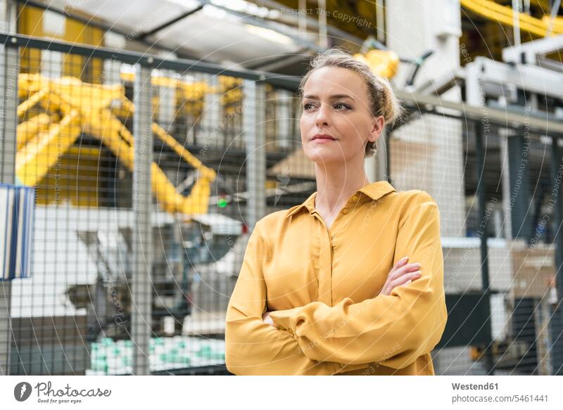 Porträt einer selbstbewussten Frau in einer Fabrikhalle mit Industrieroboter weiblich Frauen Selbstbewusstsein selbstsicher Selbstsicherheit Selbstvertrauen