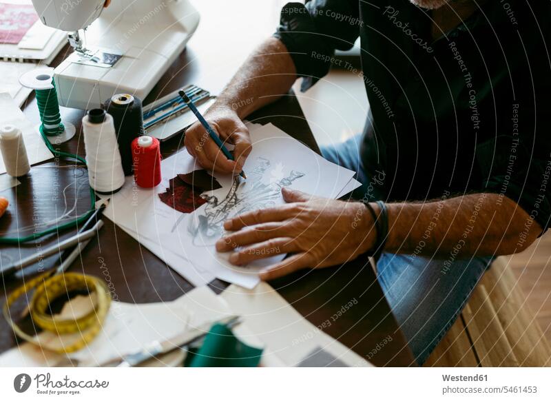 Kostümbildner beim Anfertigen einer Skizze auf Papier bei Tisch im Arbeitsatelier Farbaufnahme Farbe Farbfoto Farbphoto Innenaufnahme Innenaufnahmen innen