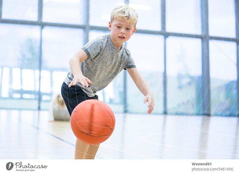 Schuljunge spielt Basketball im Sportunterricht Basketbaelle Basketbälle Schule Schulen Schüler spielen Unterricht Kindheit Unterrichtsstunde Fenster Sporthalle