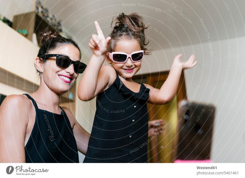 Lächelnde Mutter und Tochter tanzen, während sie zu Hause mit einem Smartphone Video aufnehmen Farbaufnahme Farbe Farbfoto Farbphoto Innenaufnahme