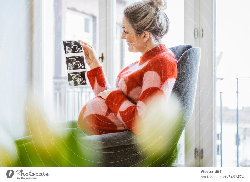Schwangere Frau hält Ultraschallbild zu Hause Leute Menschen People Person Personen Europäisch Kaukasier kaukasisch 1 Ein ein Mensch eine nur eine Person single
