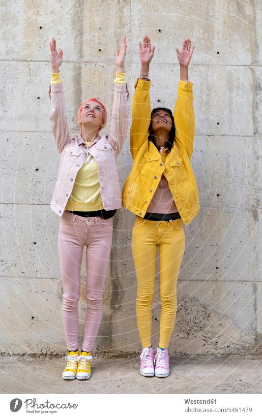 Zwei alternative Freunde tragen gelbe und rosa Jeans, posieren und heben die Arme Freundinnen Alternative homosexuell Homosexualität Homosexueller