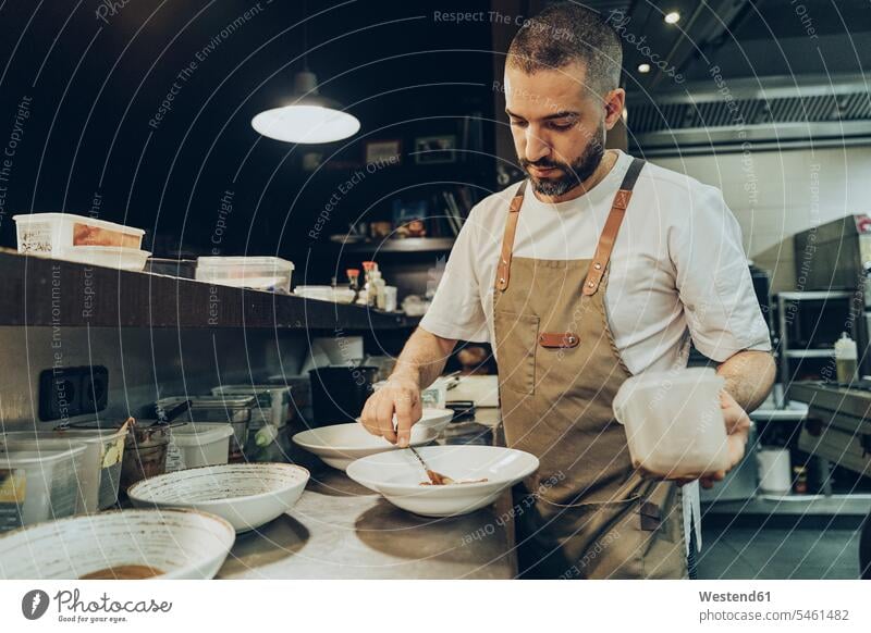 Der Koch arrangiert das Essen vor dem Servieren im Restaurant auf dem Teller Job Berufe Berufstätigkeit Beschäftigung Jobs Gastronomie Koeche Kuechenchef