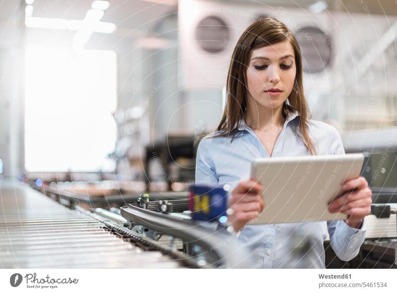 Managerin benutzt digitales Tablett, während sie in der Fabrik an der Produktionslinie steht Farbaufnahme Farbe Farbfoto Farbphoto Österreich Innenaufnahme